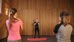 Fitness instructor leading a training session with two women in a modern gym setting.